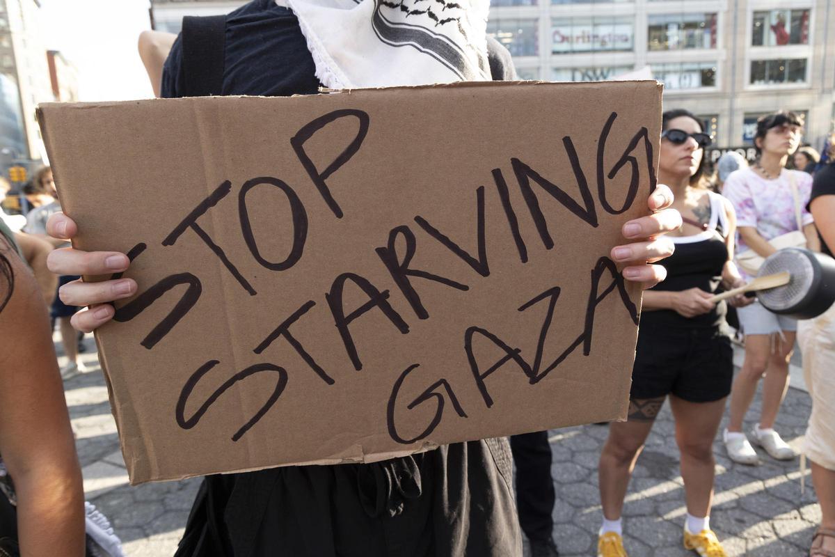 Un manifestante sosteniene un cartel que reza "Detengan el hambre en Gaza"