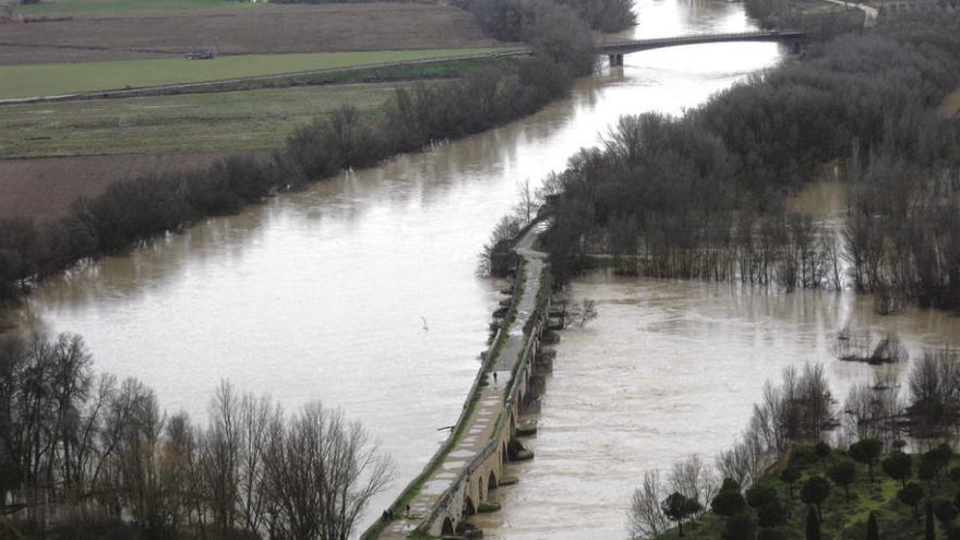 Vista general del río a su paso por el puente de piedra desde el que varios vecinos observan la crecida. Foto