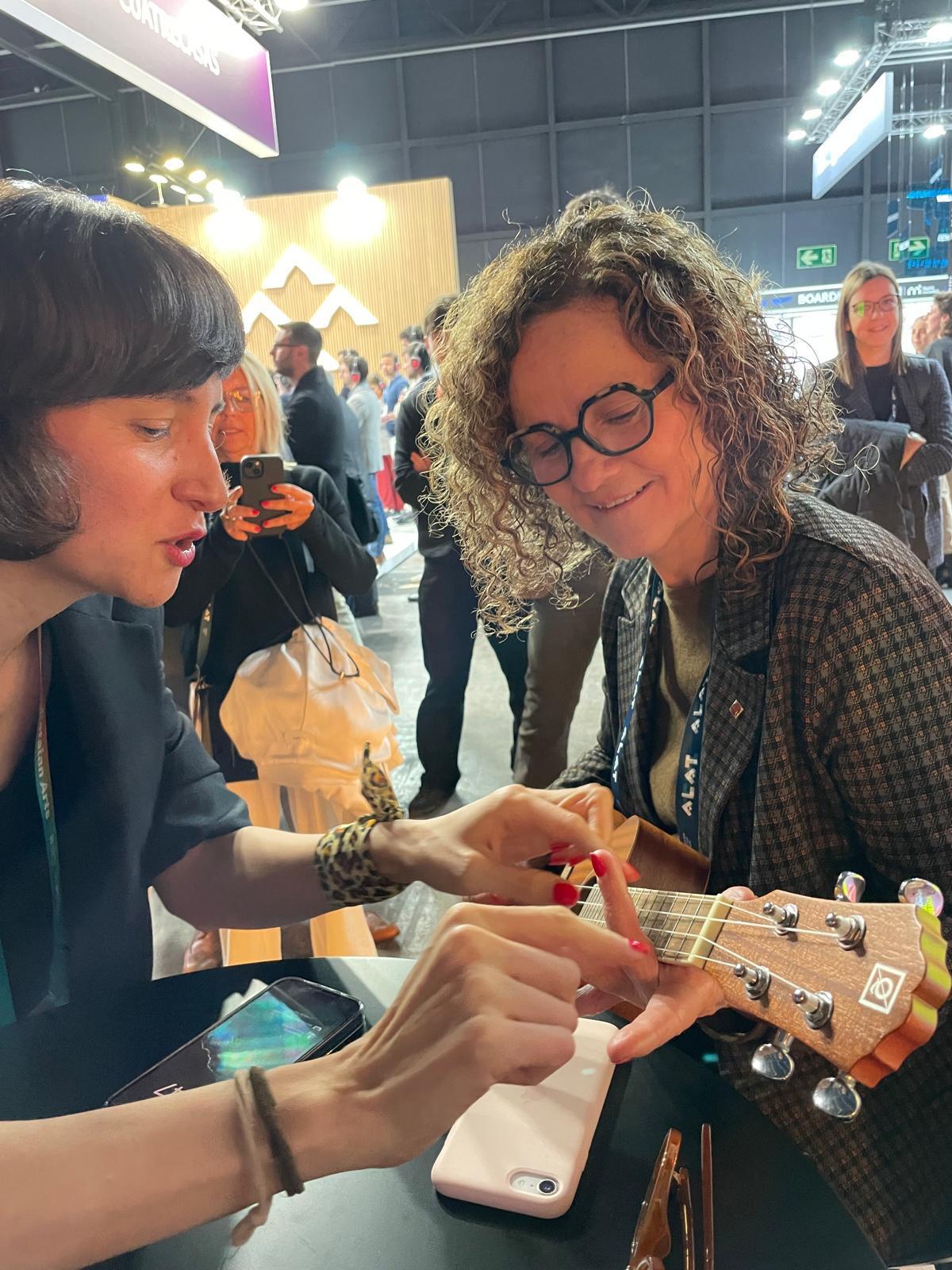 Mia Salazar da clases de ukelele a la 'consellera' de Cultura, Sònia Hernández, en el MWC.