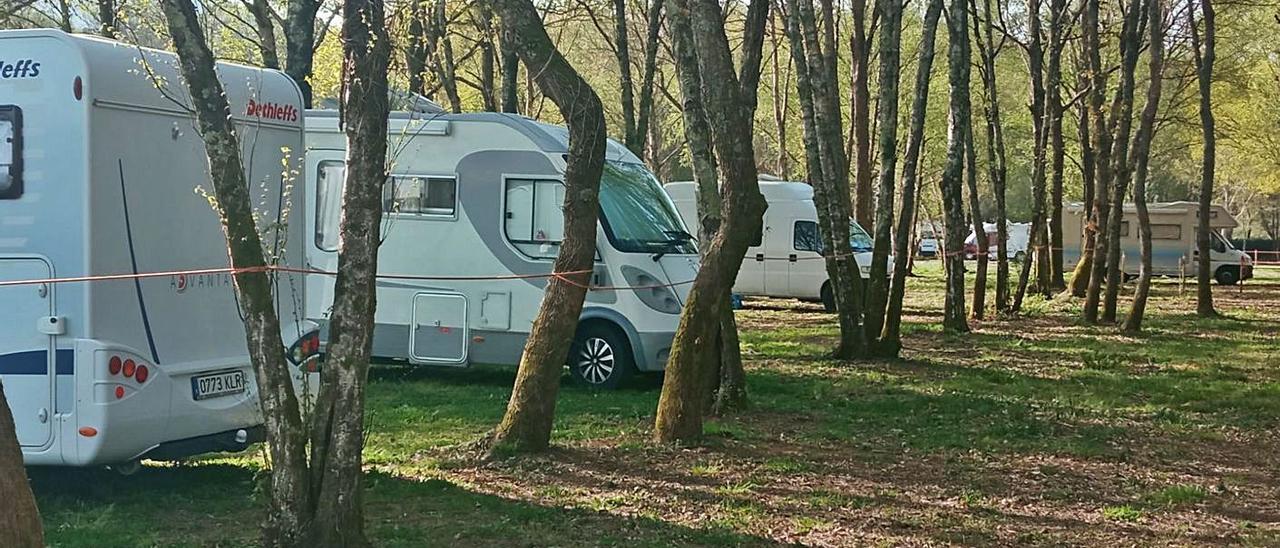 Caravanas en el espacio creado por Entre as Pontes. Coches en el aparcamiento de A Praíña y gente disfrutando del río. Izquierda, Charanga Ardores en Lalín.