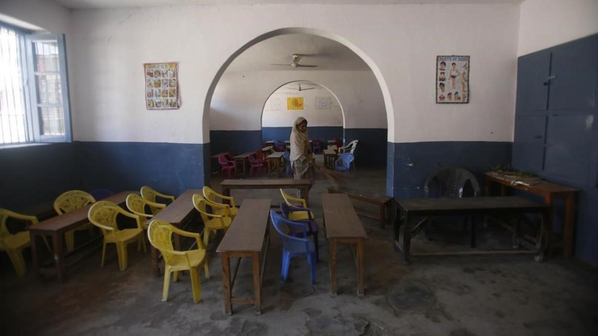 Un miembro del personal escolar limpia una aula desierta de una escuela de Cachemira controlada por los indios, Srinagar, 19 de agosto de 2019