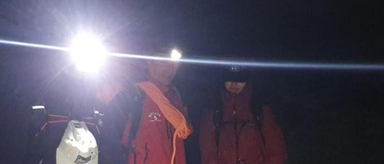 Uno de los miembros del equipo de rescate, con los dos montañeros, en la madrugada del domingo al lunes. | SEPA