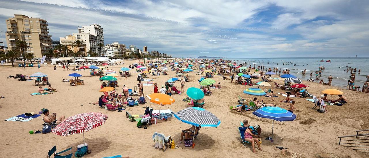 Cientos de turistas toman el sol en la playa de Gandia y otros se dan un baño o pasean por la orilla, en una imagen reciente. | NATXO FRANCÉS