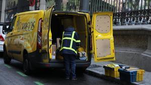 Un trabajador de Correos extrae de su furgoneta paquetes y cartas.