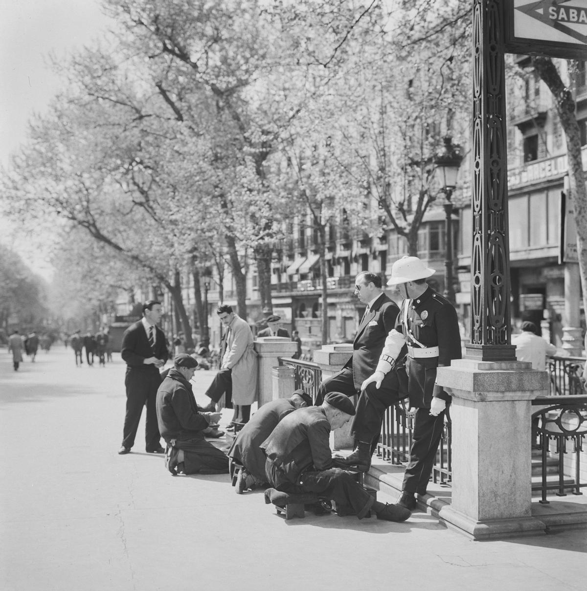 Limpiabotas trabajando junto a la entrada del metro de Plaça Catalunya. Barcelona 1955-1965