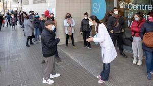 Una sanitaria atiende a un hombre en la entrada del CAP Maragall, frente a una larga cola para hacerse test de antígenos, el 27 de diciembre del 2021.