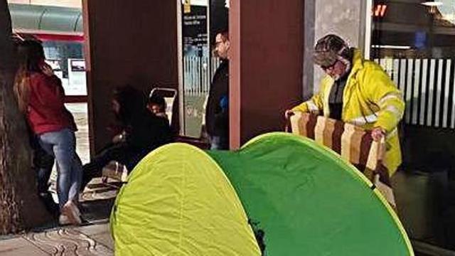 Membres de les colles van fer cua acampats davant l'oficina de turisme.