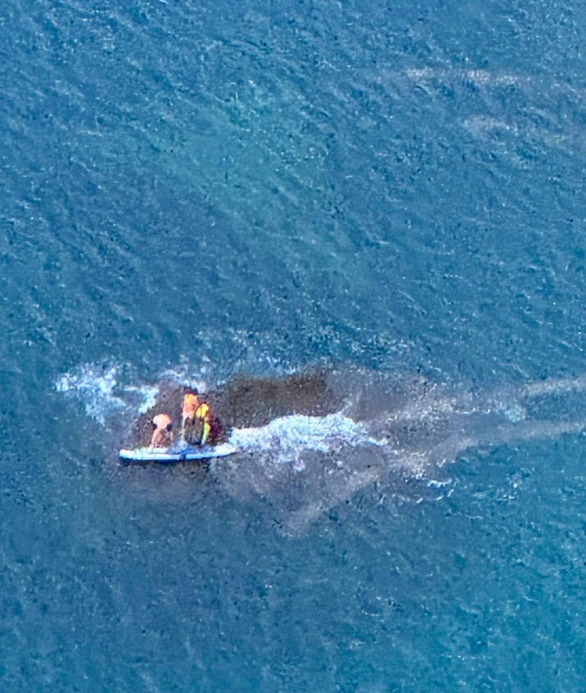 El rescatador llega hasta los bañistas, que seguían agarrados a la tabla de paddle surf