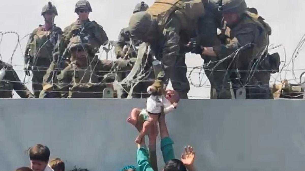 Un bebé es entregado al ejército estadounidense sobre el muro perimetral del aeropuerto para que sea evacuado, en Kabul.