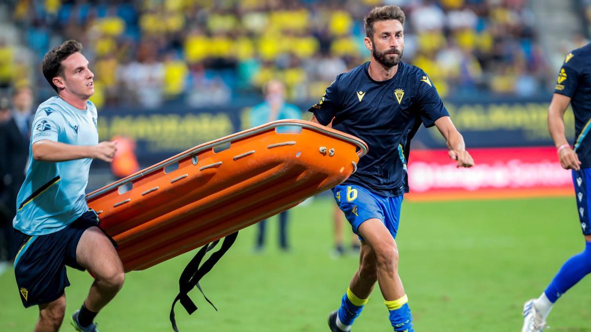 Dos jugadores del Cádiz corren para llevar una camilla hacia la grada donde el espectador había sufrido el paro cardiaco.