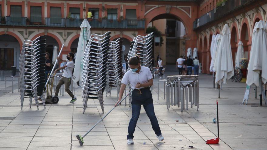 Una trabajadora de la hostelería barre una terraza en la plaza de la Corredera.