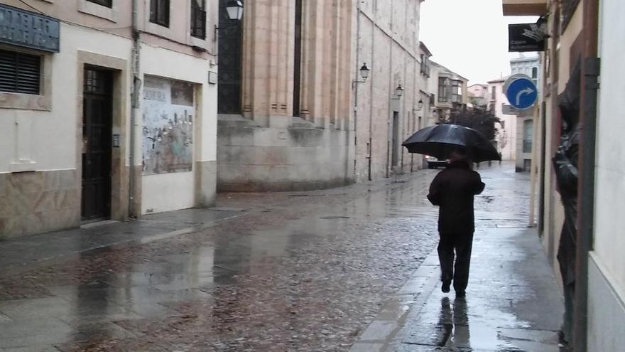 Un peatón se protege de la lluvia bajo un paraguas en el casco antiguo