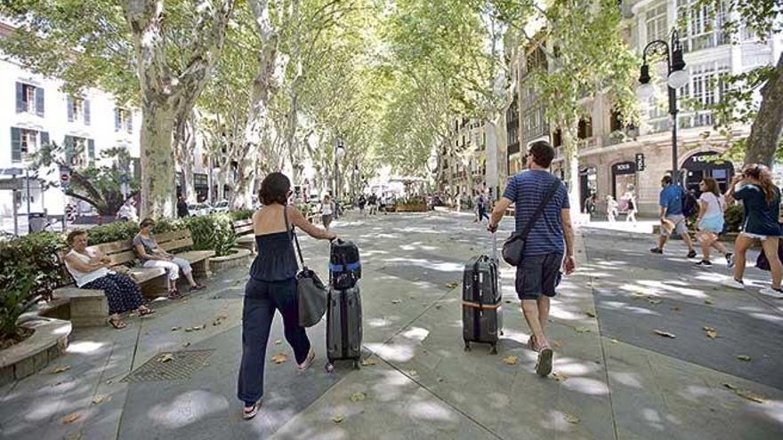 Dos turistas caminan con sus maletas por el Passeig del Born, en Palma.