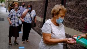 Una mujer se lava con gel hidroalcohólico antes de realizarse un test PCR en el Raval, Barcelona.