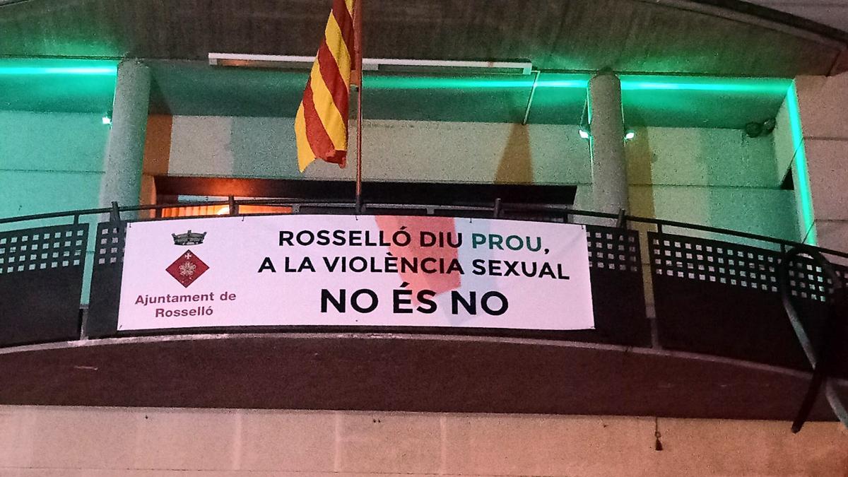 Façana de l&#039;Ajuntament de Rosselló il·luminada de verd i amb una pancarta en senyal de rebuig de les agressions sexuals