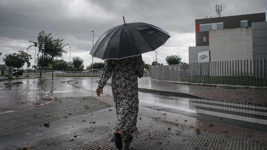 Mujer caminando con un paraguas bajo la lluvia.