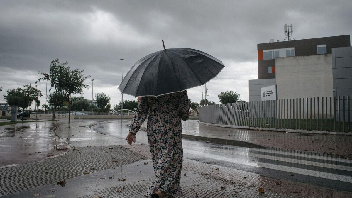Mujer caminando con un paraguas bajo la lluvia.