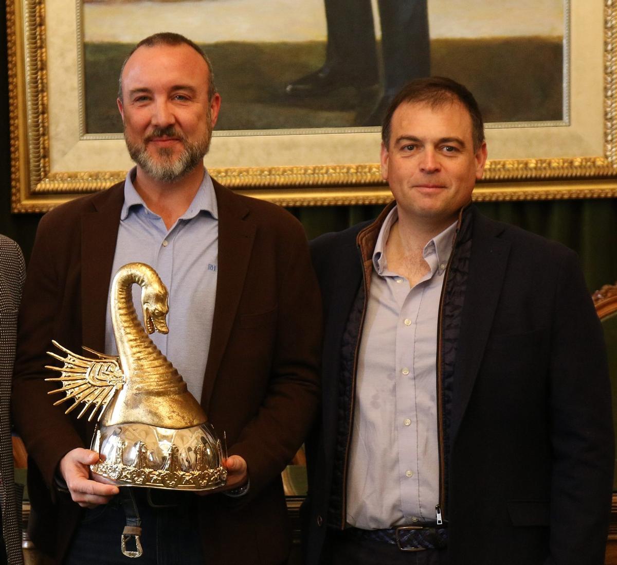 Héctor Prades, actual prohom con el casco del rey Jaime I, junto al anterior máximo representante, Luis Oria.