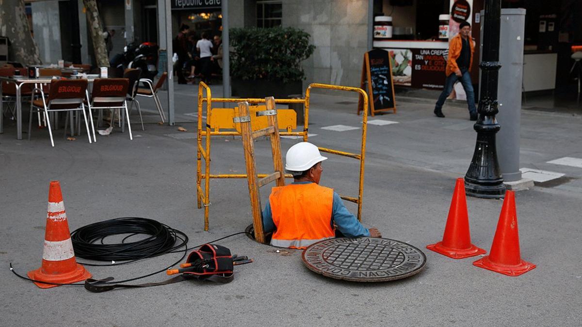 Un operario instala cable de fibra óptica en el Poblenou