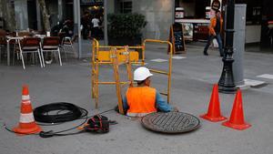 Un operario instala cable de fibra óptica en el Poblenou.