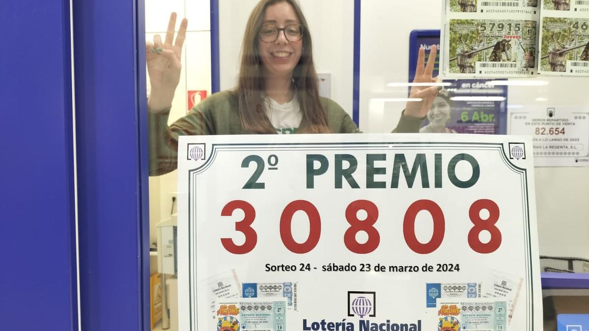 Claudia Arca, empleada de la Administración, tras el cartel con el número premiado.