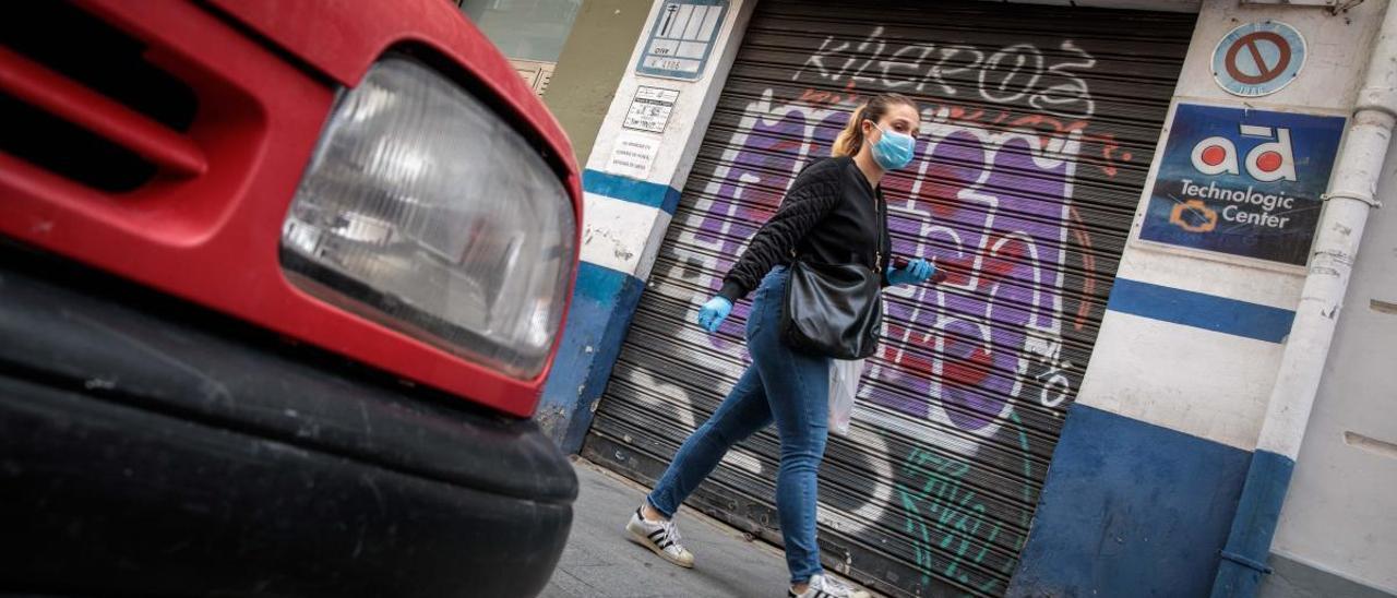 Una mujer anda por delante de un taller cerrado en València, ayer.