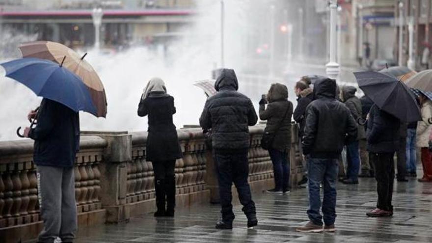 Un grupo de personas observa el temporal marítimo en el Muro de San Lorenzo, en Gijón, ayer.