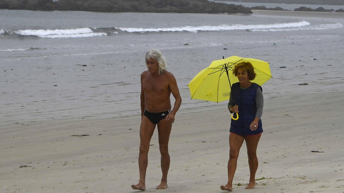 Una pareja pasea bajo la lluvia en Samil, este miércoles