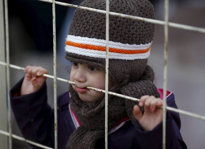 A Syrian boy looks through a gate as others wait to cross into Syria at Oncupinar border crossing in the southeastern city of Kilis