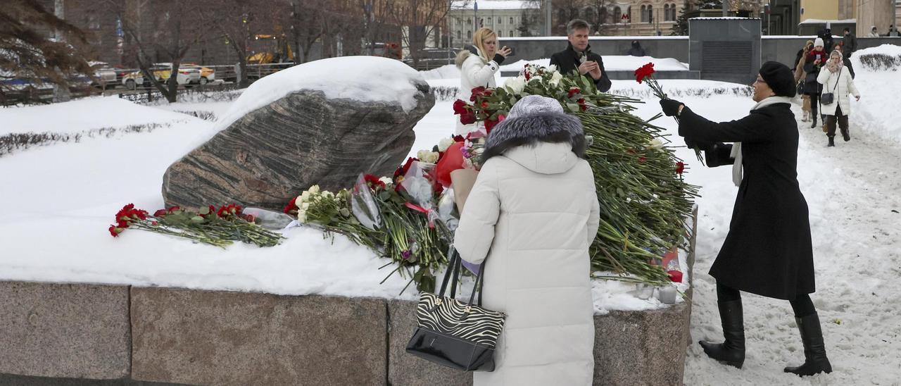Dos mujeres depositan flores en homenaje a Alekséi Navalni en la plaza Lubyanka de Moscú.
