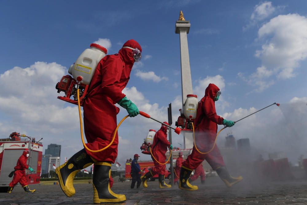 Firefighters wearing protective suits spray ...