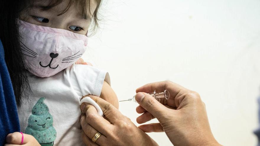 Una sanitaria pone una vacuna a una niña.