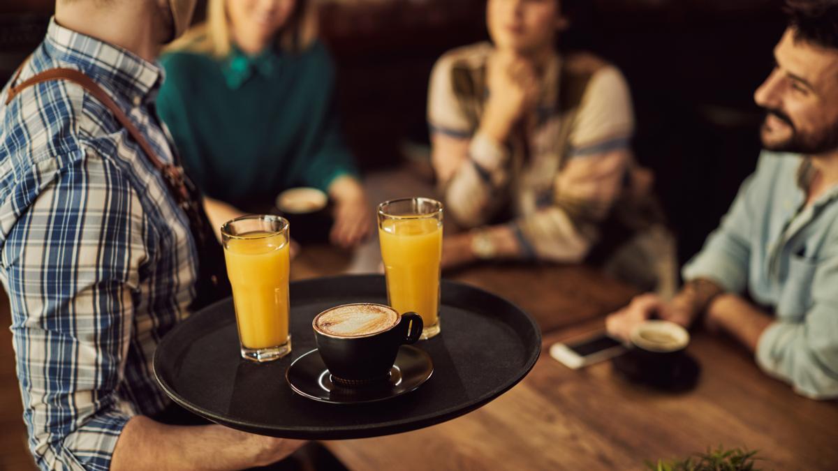 Un camarero lleva bebidas en una bandeja