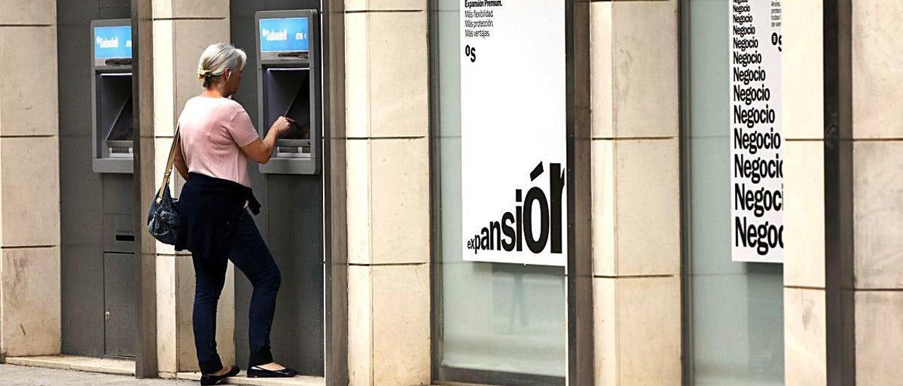 Una mujer saca dinero de un cajero de València, en una imagen de archivo.