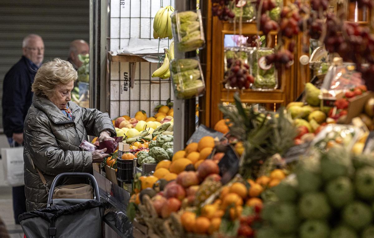 Una mujer compra frutas y verduras en un puesto del Mercado Central de Alicante