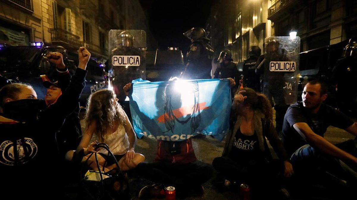 Varios policías vigilan a un grupo de jóvenes sentados en la calzada para protestar contra la sentencia, este sábado en el centro de Barcelona