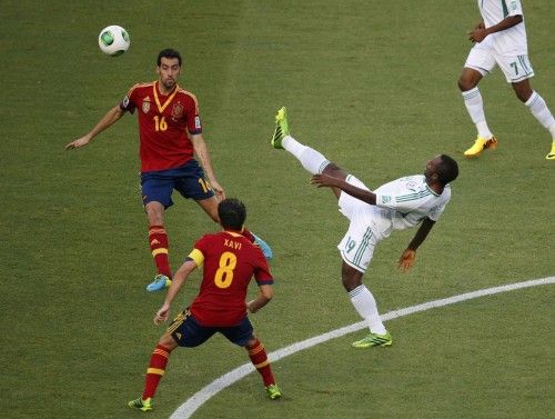 Nigeria's Mba kicks the ball near Spain's Busquets and Xavi during their Confederations Cup Group B soccer match at the Estadio Castelao in Fortaleza