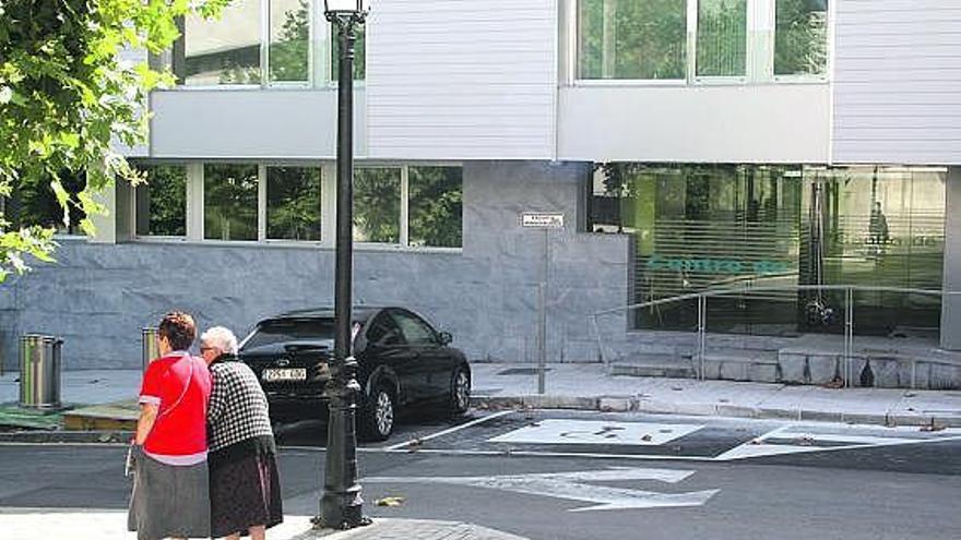 Dos personas mayores pasean delante del centro de día de Candás, cuya obra ya ha finalizado.