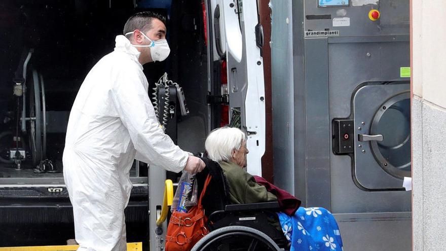 Un trabajador traslada a una anciana no contagiada por coronavirus.