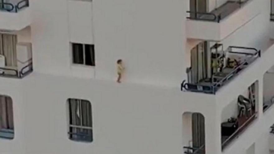 La niña pasea por una cornisa en unos apartamentos en Tenerife.