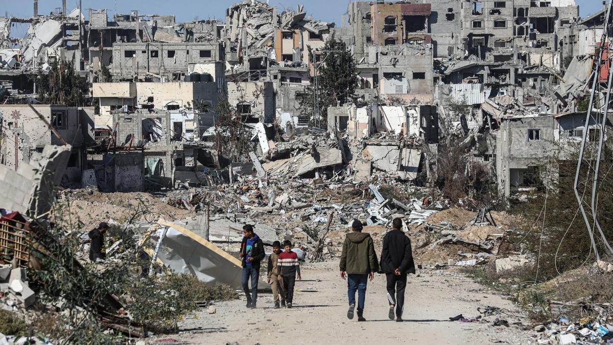 Un grupo de palestinos camina entre edificios destruidos por los ataques del Ejército de Israel contra el campamento de refugiados de Bureij, en Deir al Balá, situada en el centro de la Franja de Gaza
