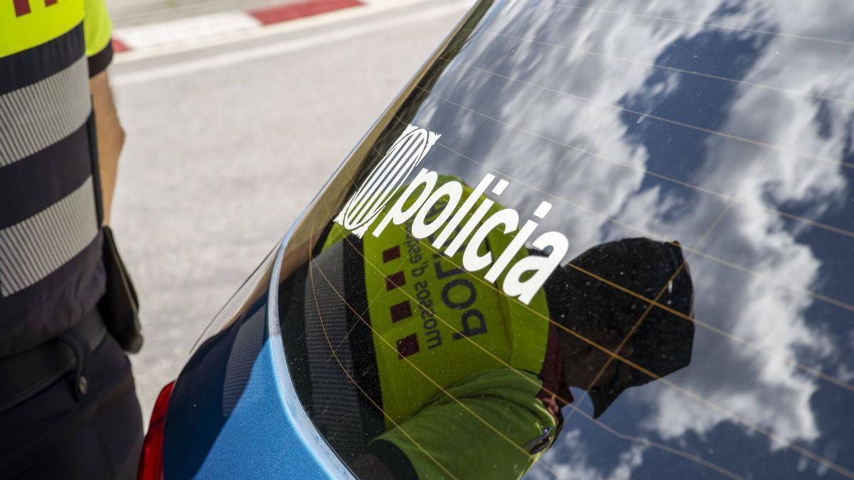Un agent dels Mossos d'Esquadra davant d'un vehicle policia.