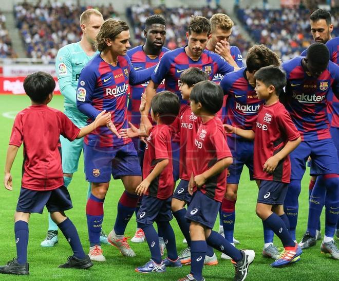 Antoine Griezmann, Samuel Umtiti y Sergi Roberto saludan a unos niños antes del comienzo del primer partido de pretemporada del FC Barcelona contra el Chelsea, amistoso correspondiente a la Rakuten Cup y disputado en el estadio Saitama.