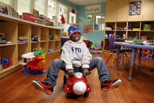 Dunia Sibomana, 8, who was attacked two years ago by a chimpanzees in his village in the Democratic Republic of Congo, rides on a toy car at Stony Brook Children's Hospital in Stony Brook, New York
