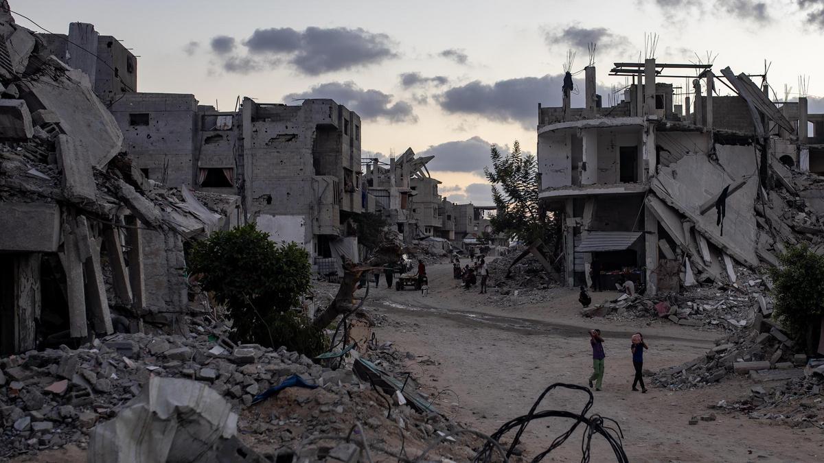 Palestinos junto a las ruinas de edificios destruidos por ataques de Israel en Yan Junis (Gaza).