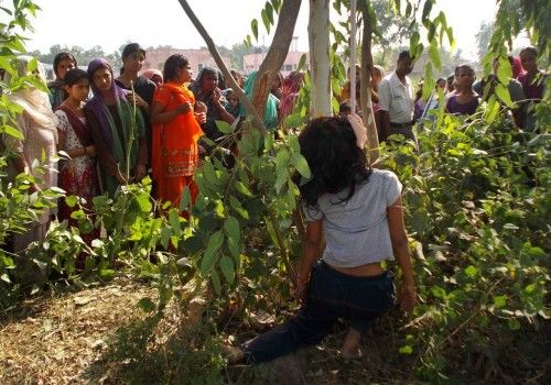 Onlookers look at the body of a woman, hung from a tree, in Moradabad