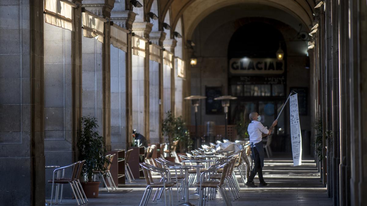 Un camarero cuelga un cartel junto a una terraza de la plaza Reial, en Barcelona, en diciembre de 2020.