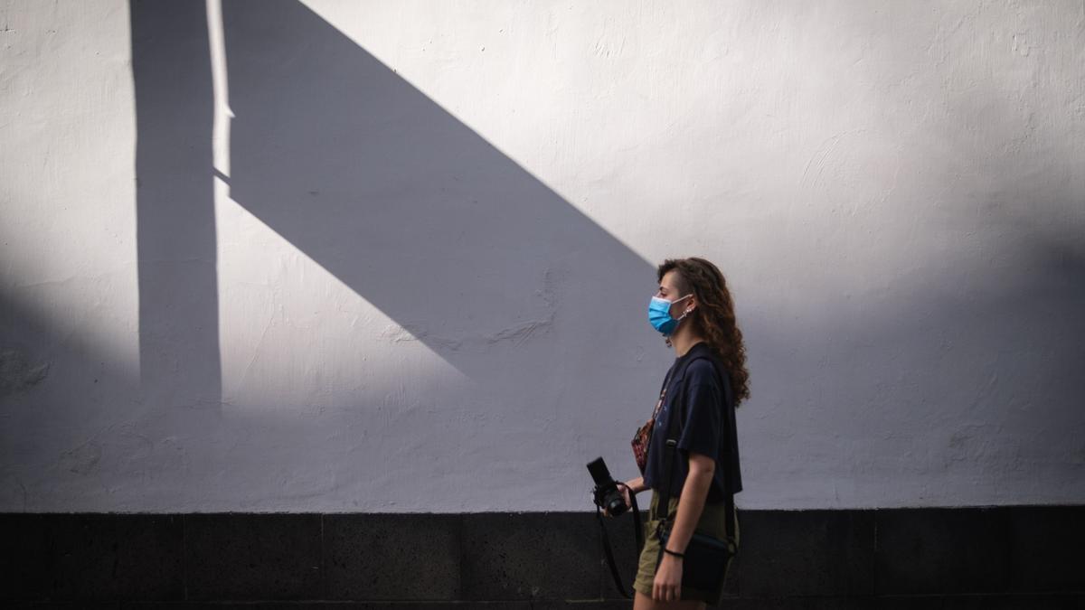 Una chica con mascarilla para protegerse del coronavirus pasea por Santa Cruz.