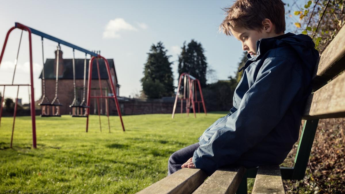 Niño víctima de acoso escolar en un parque.