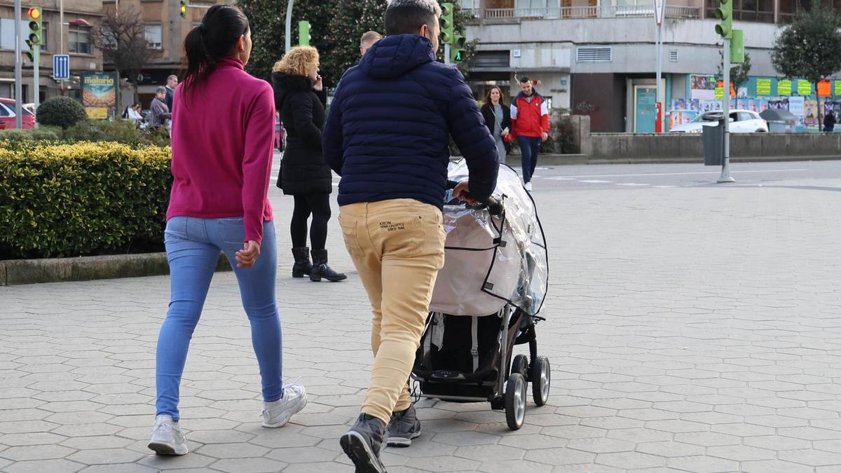 Una pareja pasea con un carrito de bebé.